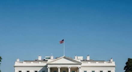 United States flag flies atop a classic white building against a clear blue sky, symbolizing the nation's capital.
