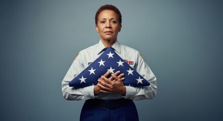Woman in military uniform holding a folded american flag in honor of independence day and a deceased veteran.