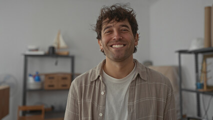 Fototapeta premium Smiling man holding house keychain, symbolizing new home ownership in a warm indoor setting.