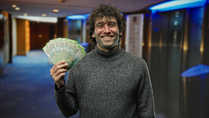 Hispanic man at hotel reception holding russian banknotes indoors displaying wealth with a joyful...