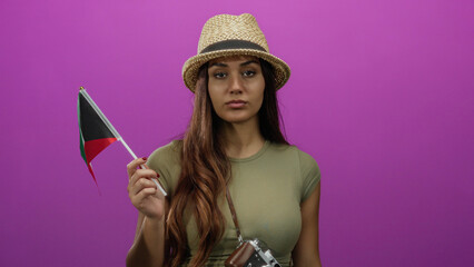 Woman holding kuwait flag on pink background wearing hat conveying travel and cultural pride.