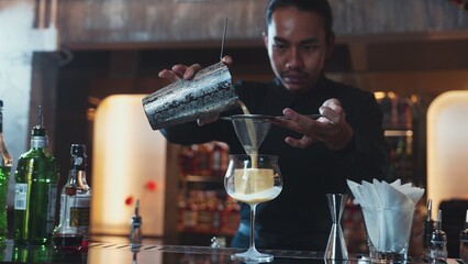 Asian bartender using strainer all ingredients alcohol liquor and syrup tasty in cocktail glass...