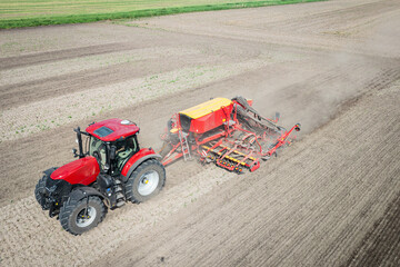 Traktor mit moderner Direkt - Sämaschine beim Drillen auf einem staubigen Feld, Luftbild.
