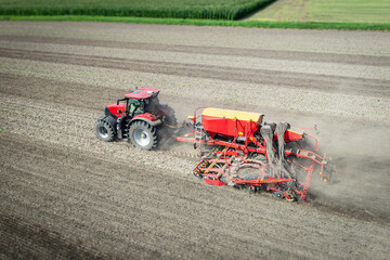 Traktor mit moderner Direkt - Sämaschine beim Drillen auf einem staubigen Feld, Luftbild.