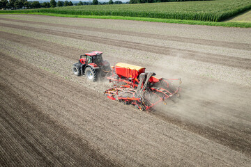 Traktor mit moderner Direkt - Sämaschine beim Drillen auf einem staubigen Feld, Luftbild.