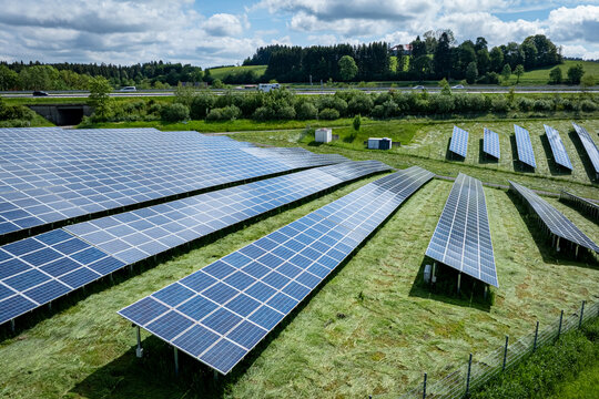 Gro&szlig;e Freifl&auml;chen-PV Anlage entlang einer Autobahn im Sonnenschein, Luftbild.