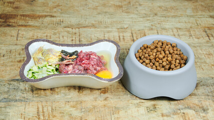 Natural raw dog food and kibble in bowls on wooden background Dog food