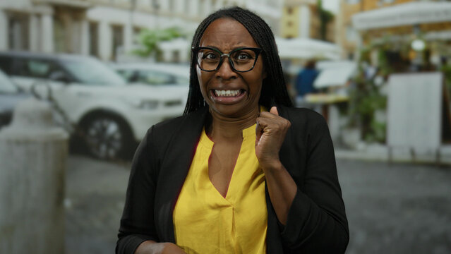 Woman with glasses in yellow shirt looks shocked on urban street background with cars and buildings visible creating a tense moment in the city.