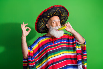 Mature man in traditional Mexican attire wearing sombrero and poncho, holding a playful gesture...