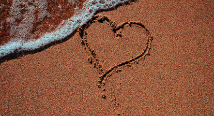 Heart shape drawn on sand on seashore