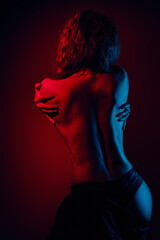 Woman studio posing with bare back, vibrant red and blue lights