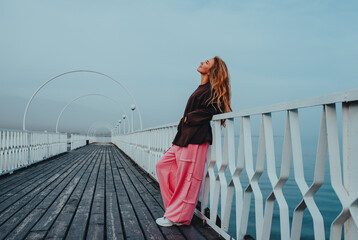 Young beautiful woman posing on pier on lake shore