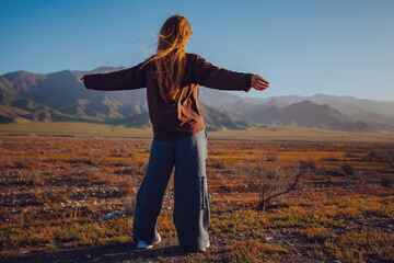 Young beautiful woman posing in the mountains on sunny day, freedom concept