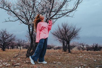 Young woman walking under blooming tree in spring