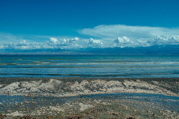 Issky-kul lake in Kyrgyzstan, summer picturesque landscape with small shells on shore
