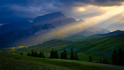 Dramatic mountain landscape at sunrise or sunset, featuring a panoramic view of misty hills and cloud-kissed peaks under a vibrant sky