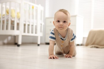 Cute little baby crawling on floor at home, space for text