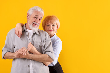 Lovely senior couple together on yellow background, space for text