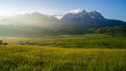 Fototapeta premium Dramatic mountain landscape at sunrise or sunset, featuring a panoramic view of misty hills and cloud-kissed peaks under a vibrant sky