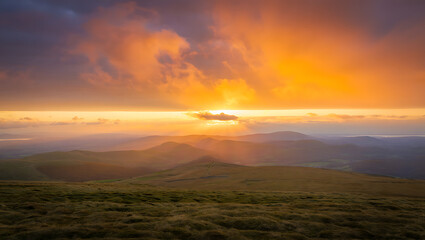 Obraz premium Dramatic mountain landscape at sunrise or sunset, featuring a panoramic view of misty hills and cloud-kissed peaks under a vibrant sky