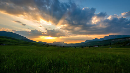 Obraz premium Dramatic mountain landscape at sunrise or sunset, featuring a panoramic view of misty hills and cloud-kissed peaks under a vibrant sky