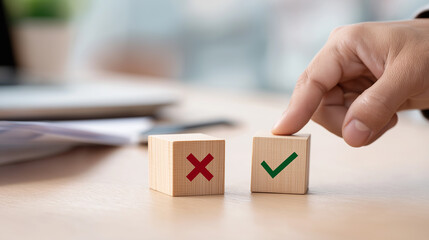 Person making a decision between wrong and right using wooden blocks with check and cross symbols.

