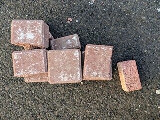 Stacked brown pavement bricks on black asphalt ground surface