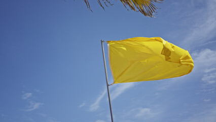 Yellow flag waving on a sunny day with clear blue sky