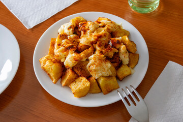 A plate of patatas bravas with aioli and spicy paprika, served on the table and ready to eat