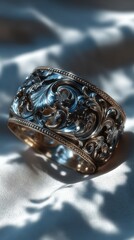 Intricately designed silver ring with blue accents resting on soft fabric in natural light
