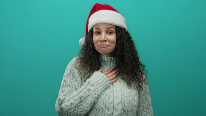 Woman wearing santa hat and sweater smiles over green background, conveying warmth and festive spirit during holiday season, showcasing joy and friendliness.