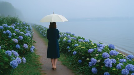 雨の中、川辺のアジサイがある道を歩く女性