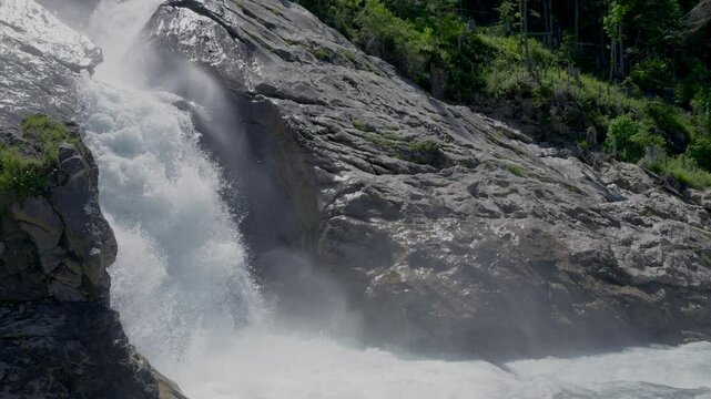 Scenic slow motion of the Simmenfalle waterfalls with huge black rocks and plants in Lenk