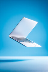 Floating laptop captures the essence of innovation and modern technology in a vibrant blue setting