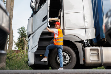 Portrait young adult happy smiling woman climbing cabin heavy truck driver cargo vehicle. Female person girl professional job career working driving freight engine lorry. Logistics industry