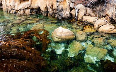 Fototapeta premium Cliff with rocks under water clear visible blue ocean shore rocky inaccessible 