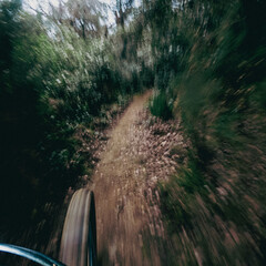 Riding a mountain bike fast on a single track in the middle of the forest front wheel and ground point of view