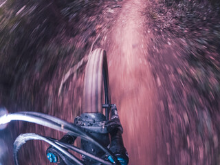 Riding a mountain bike fast on a single track in the middle of the forest front wheel and ground point of view