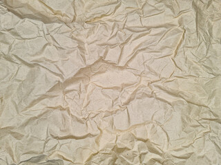 Crumpled paper texture with a soft, beige hue, featuring uneven folds and creases that create a complex abstract pattern. No text present on the surface of the paper