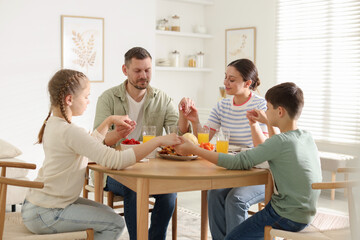 Family praying together before dinner at table indoors