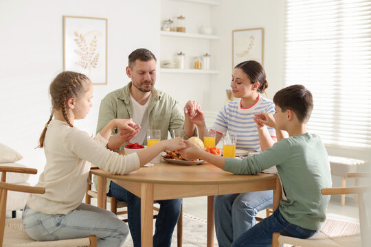 Family praying together before dinner at table indoors