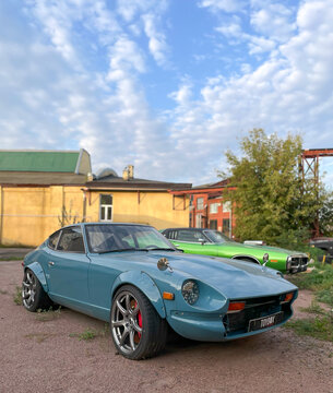 A classic custom tuned light blue Datsun 240Z Nissan Fairlady Z S30 sports car parked outdoors in an urban backyard.