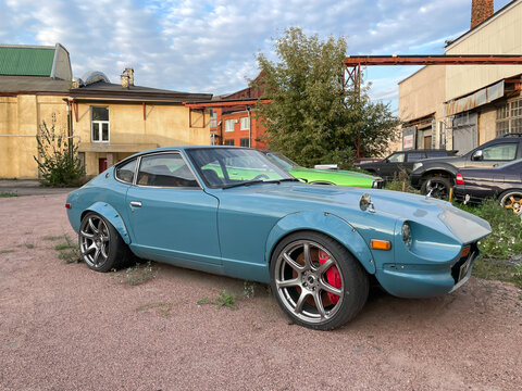 A classic custom tuned light blue Datsun 240Z Nissan Fairlady Z S30 sports car parked outdoors in an urban backyard.