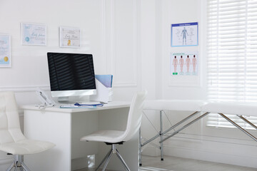 Doctor's workplace with modern computer and examination table in medical office