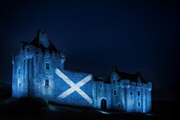 Ancient Scottish Castle at Night with Scotland Flag Projected Onto the Facade and Lit Up with Festive Blue and White Lights with Dark Sky in Background with Mock Up Space 