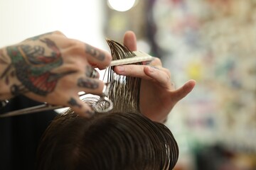 Professional barber making stylish haircut in barbershop, closeup