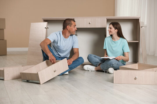 Happy couple assembling furniture on floor at home - Powered by Adobe