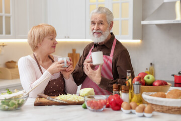 Senior couple having tea while cooking together in kitchen