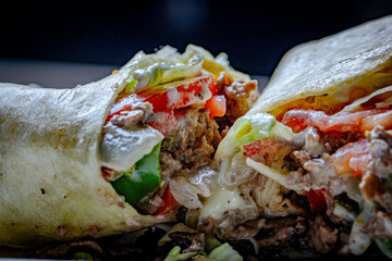 meat wrap tortilla with lettuce and tomatoes served with mayo and spicy sauce