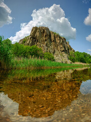 portrait view to granite rock on river in canyon under sky with huge cloud